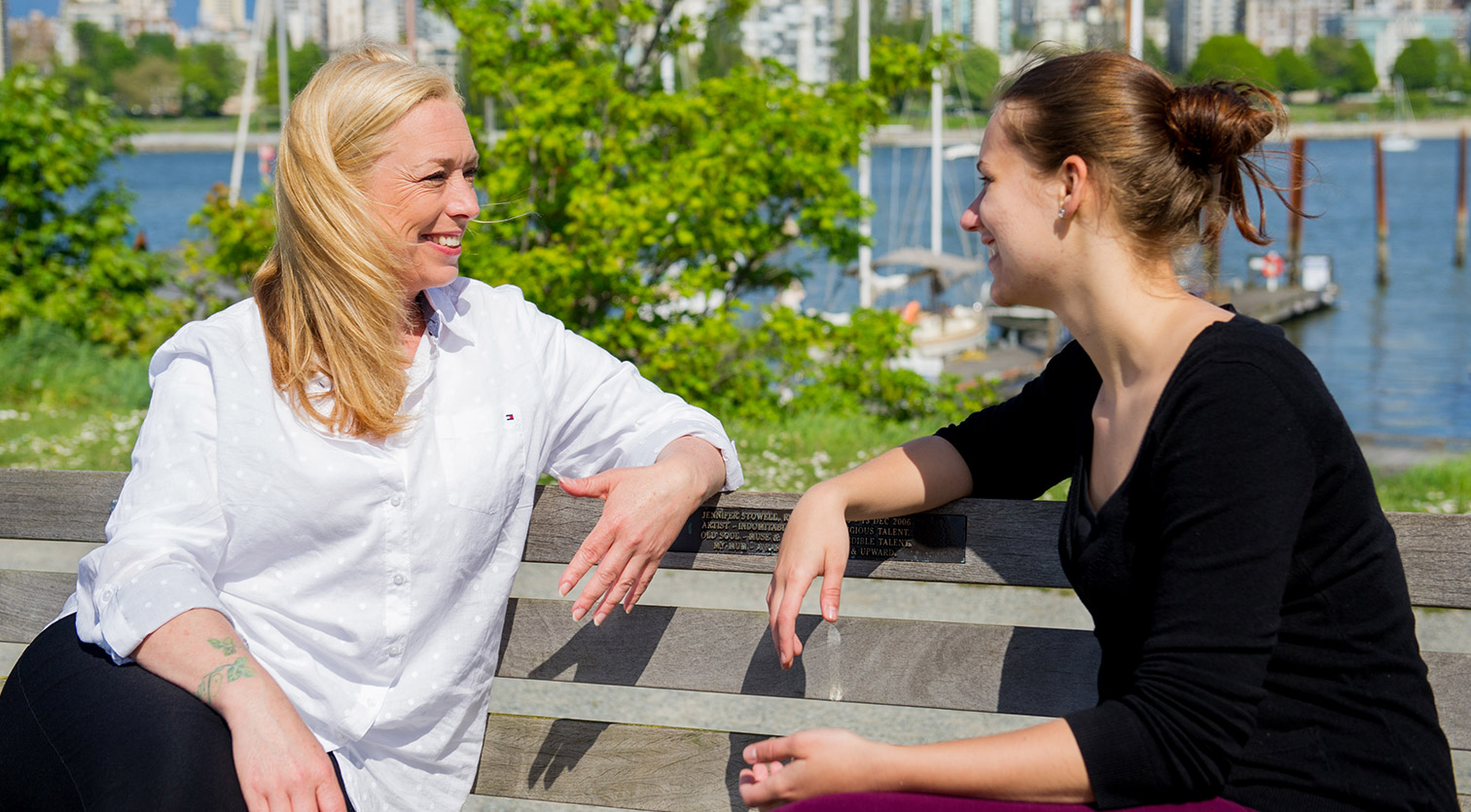 Two people in conversation outdoors on a sunny day